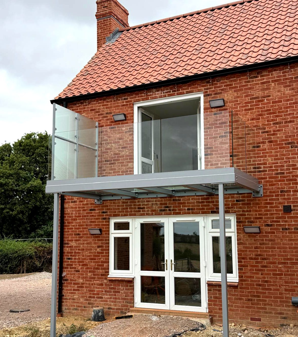 Light grey powder-coated walkout balcony with a full walk-on glass floor and frameless glass balustrade, Whissendine, Rutland